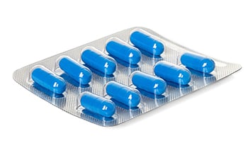 Blue capsules sealed in a medical blister pack.