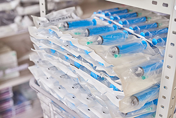 Shelves of blue needles and syringes wrapped in clear plastic.