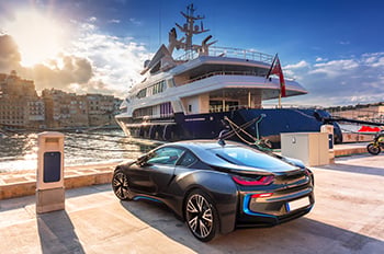 Electric sport car parked near a yacht and marina.