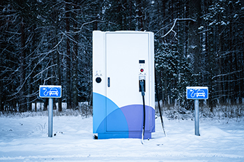 Electric car charging station in forest in winter time.