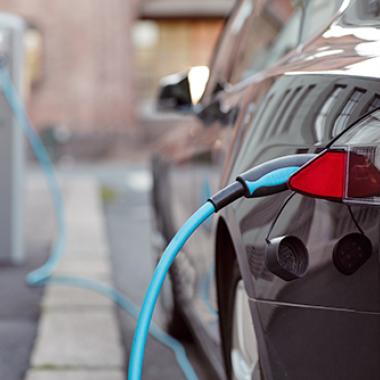 Black electric vehicle charging at charging station.