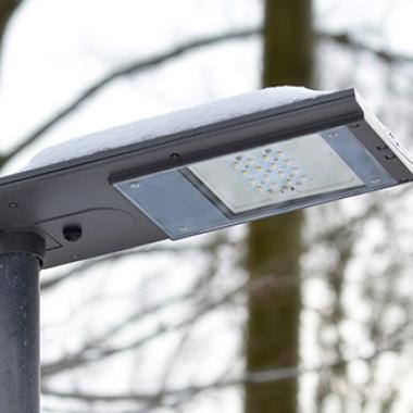 A solar powered, snow covered LED street light during cloudy weather.