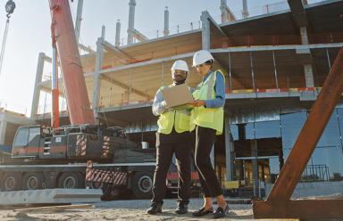 Two people looking at a laptop on a construction site