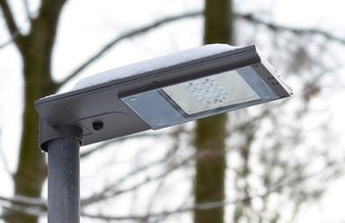 A solar powered, snow covered LED street light during cloudy weather.