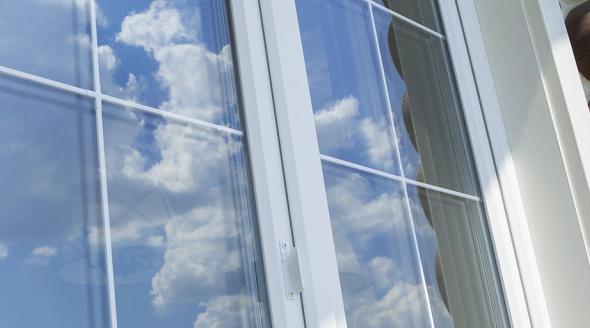 Plastic white glass panels and muntin bars on a log cabin, reflecting a blue sky and clouds.