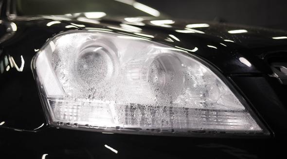Closeup of headlight on black vehicle with water ingress.