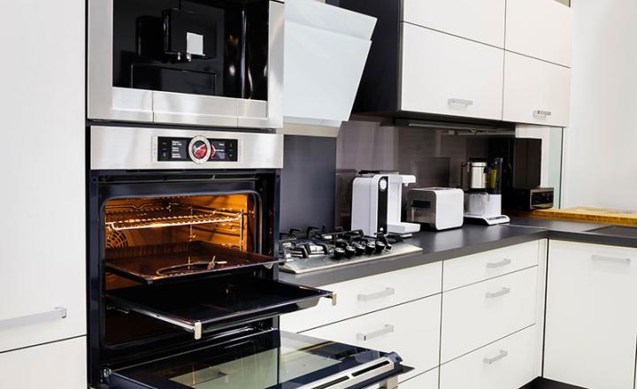 A clean, contemporary kitchen featuring cabinetry, an oven and other appliances.