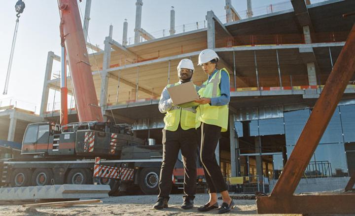 Two people looking at a laptop on a construction site
