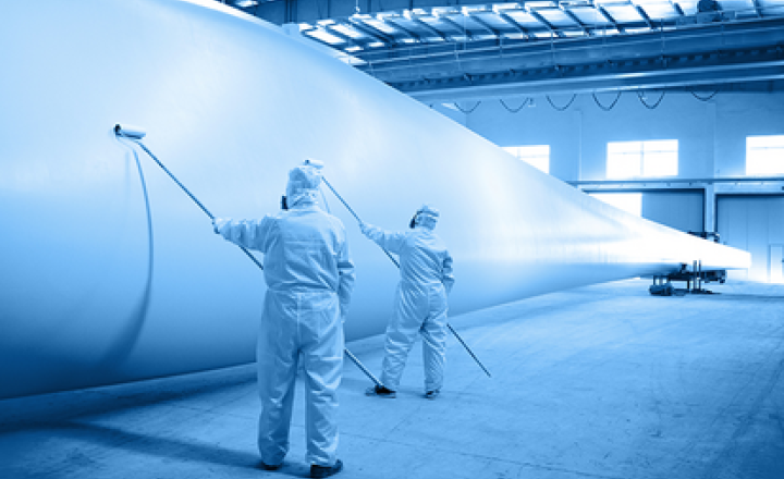 Painting a wind turbine blade inside an industrial setting.