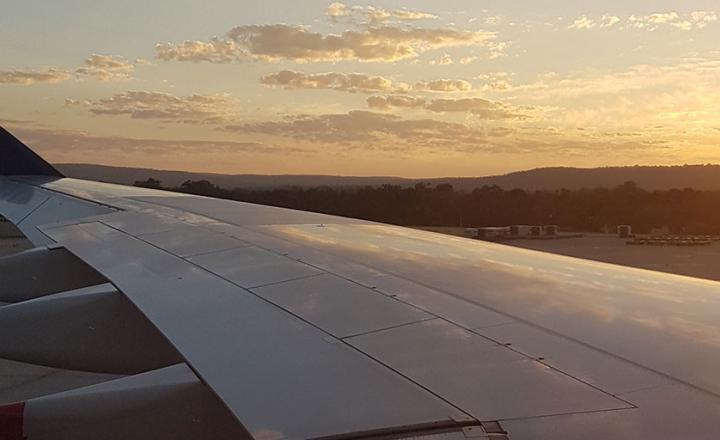 Airplane wing at sunset against a cloudy sky
