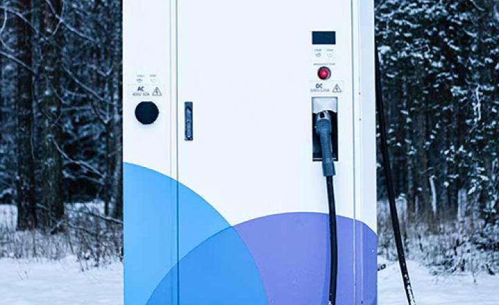 Electric car charging station in forest in winter time.