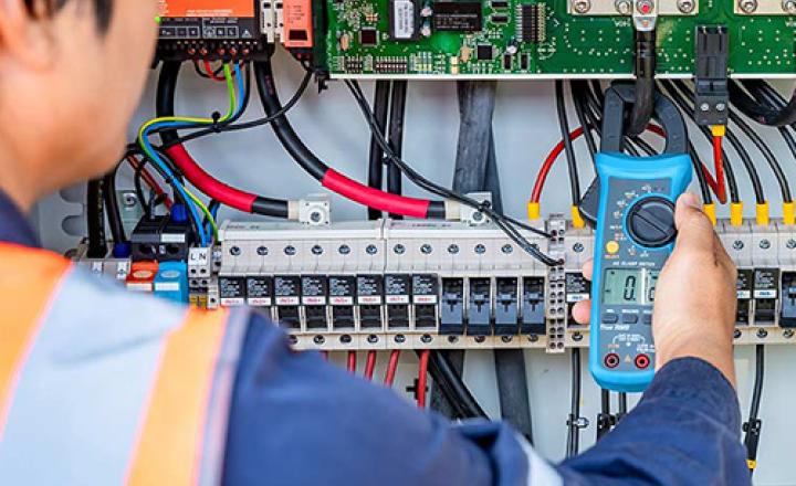 An engineer uses a multimeter to check the operation of a system on a solar farm and panel.