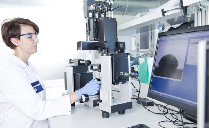 A lab technician wearing blue gloves works equipment