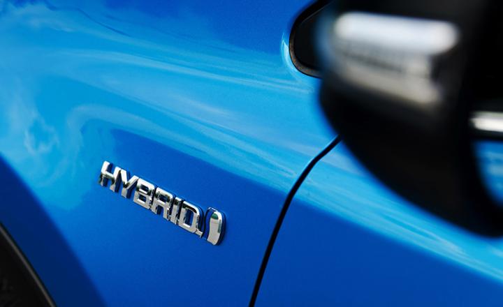 Hybrid emblem bonded to the side of a blue car