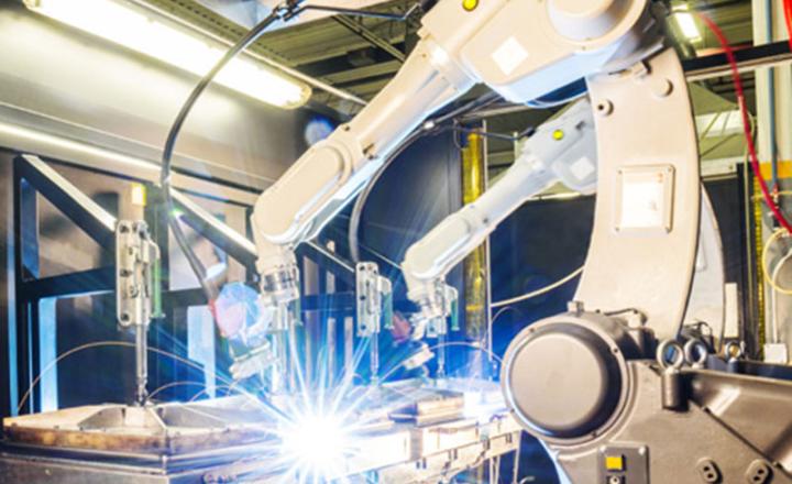 An automated robotic arm involved in thermal spray with fire sparking in an industrial setting.