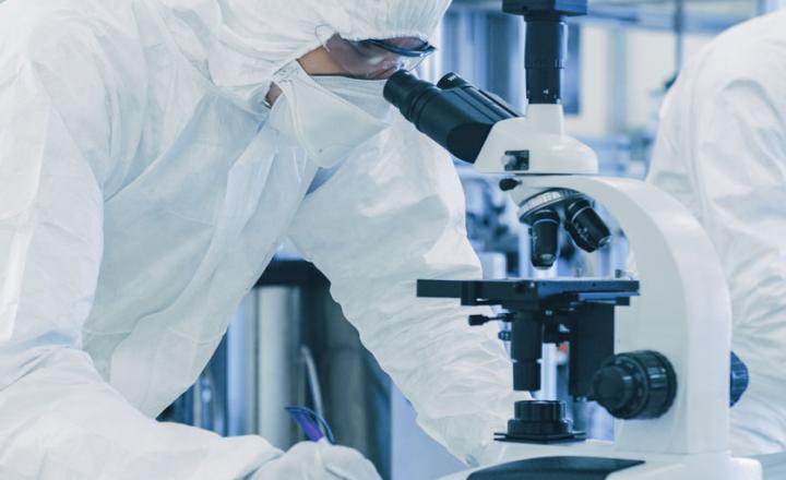Scientists in protective clothes performing research using microscopes in a laboratory