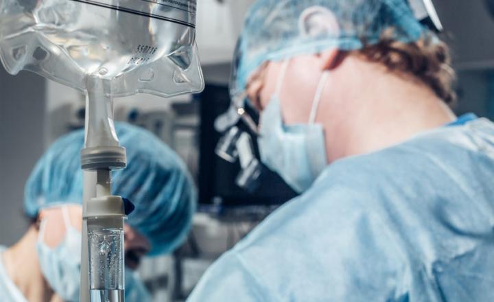Masked surgeon and assistant performing surgery in hospital operating room