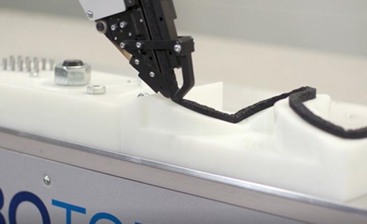 An industrial robot applying foam tape to curved surfaces.