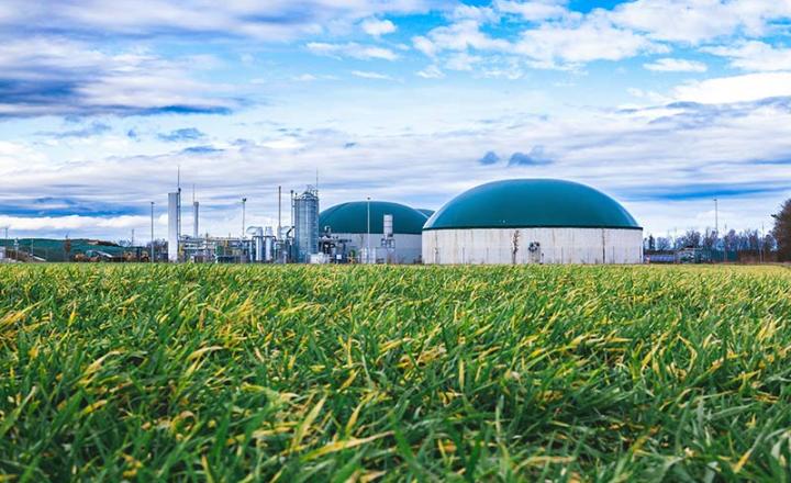 A modern biomass energy production site next to a green field
