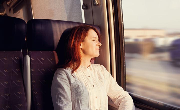 A woman with closed eyes enjoying the comfort of travelling in a train