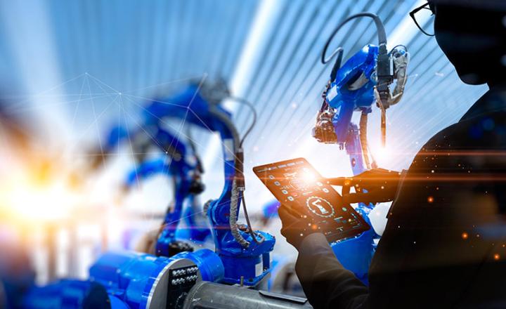 A worker using high-end technology to control robotic applications in an intelligent factory.