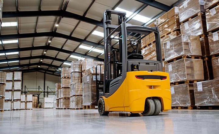 Forklift in warehouse in the middle of stored goods and stacked pallets.