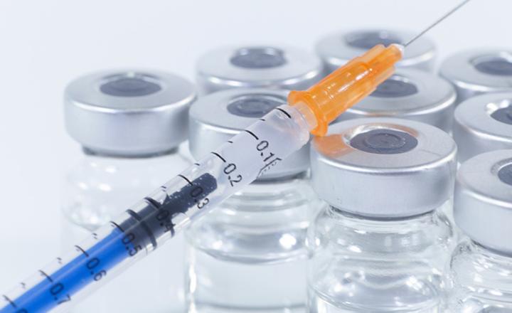 Medical supplies featuring a syringe and glass vials and bottles.