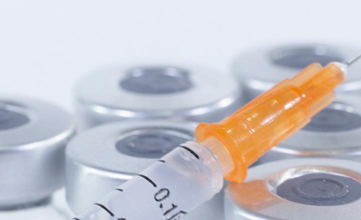 Medical supplies featuring a syringe and glass vials and bottles.