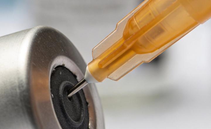 Medical syringe piercing rubber stopper of vaccine vial.