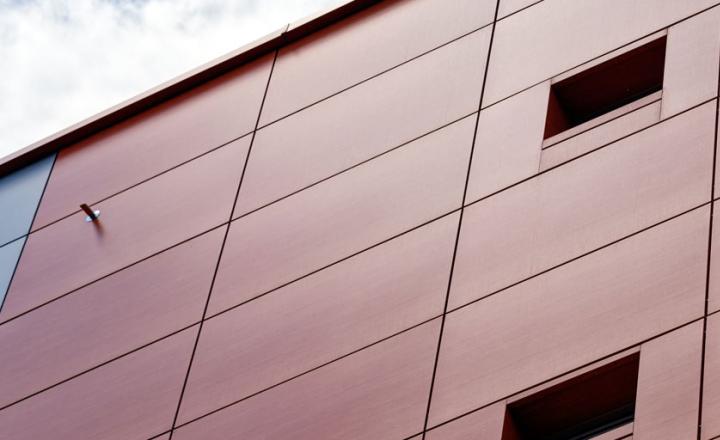 Outside view of the corner of a modern building with grey metal cladding façade and windows
