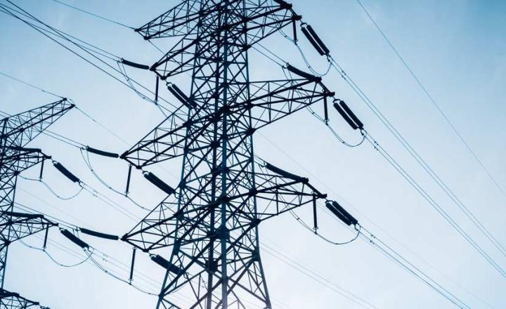 Rows of electric transmission pylons against blue sky.
