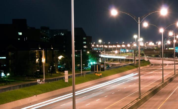 Illuminated LED powered highway lamps at an empty road at night