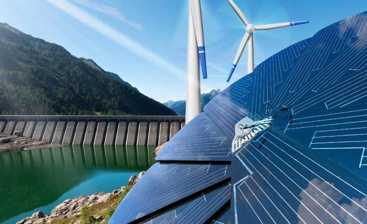 Hydro-power dam with solar panels and wind turbines against mountains and blue sky