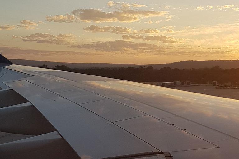 Airplane wing at sunset against a cloudy sky