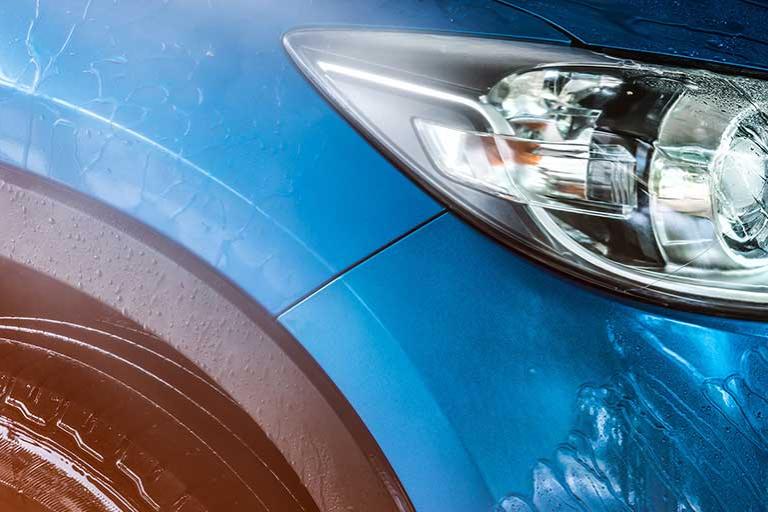 Blue compact SUV car with sport and modern design being washed with water