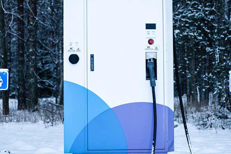 Electric car charging station in forest in winter time.