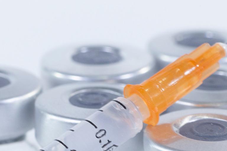 Medical supplies featuring a syringe and glass vials and bottles.