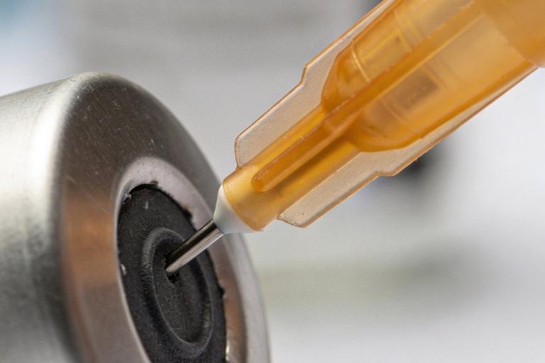 Medical syringe piercing rubber stopper of vaccine vial.