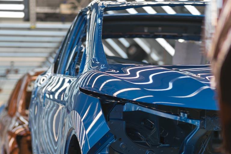 A blue car on a vehicle production line.