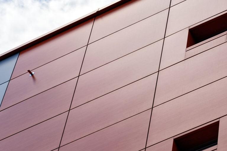 Outside view of the corner of a modern building with grey metal cladding façade and windows