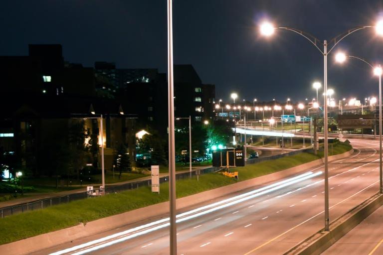 Illuminated LED powered highway lamps at an empty road at night
