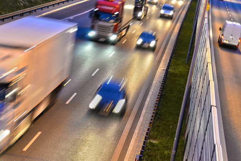 Cars and trucks driving in both directions on a highway with their lights on. Cars and trucks driving in both directions on a highway with their lights on.