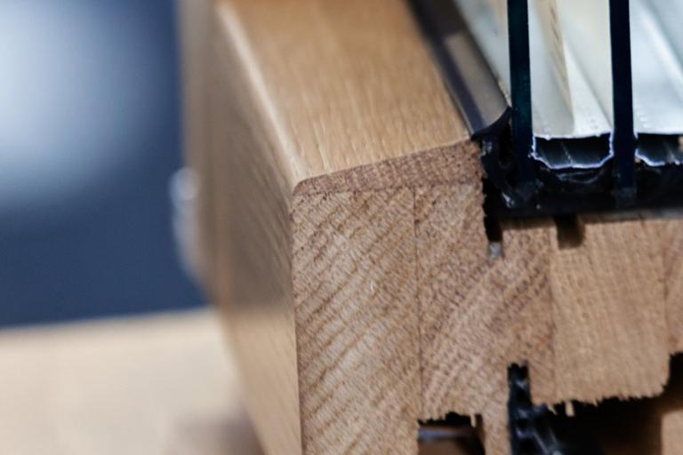 Close-up view of a wooden window frame showing the design of the window and its parts with spacers and isolation between multiple glass layers