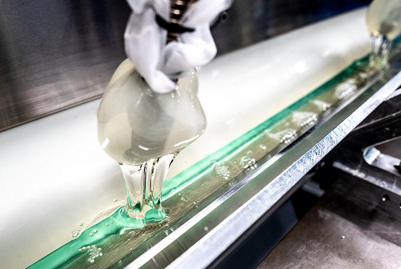 Clear, thick liquid filling a long, stainless steel reservoir piece of equipment.