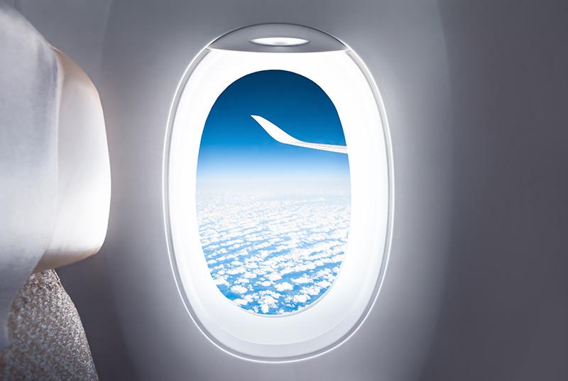 Airplane window view of sky and wing of plane