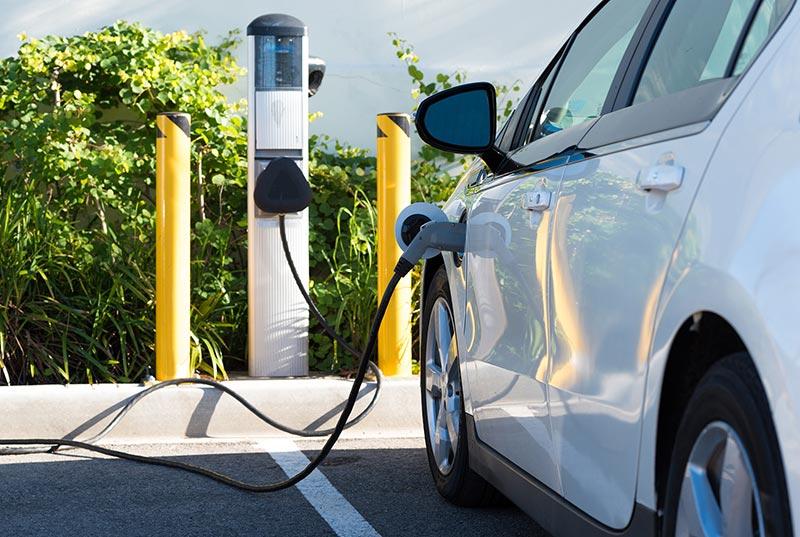 A white electric vehicle charging at a charging station.