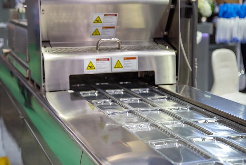 Linear food plastic tray package heat sealing machine in the food industry.