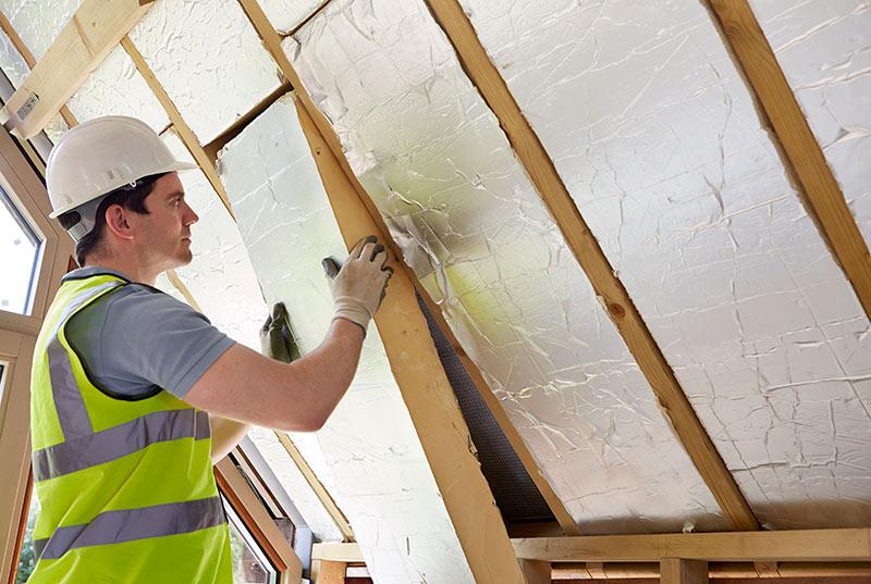 A construction worker installing insulation inside a building.