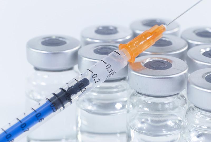 Medical supplies featuring a syringe and glass vials and bottles.