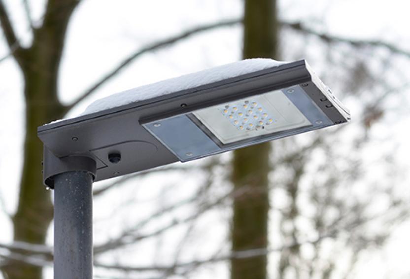 A solar powered, snow covered LED street light during cloudy weather.